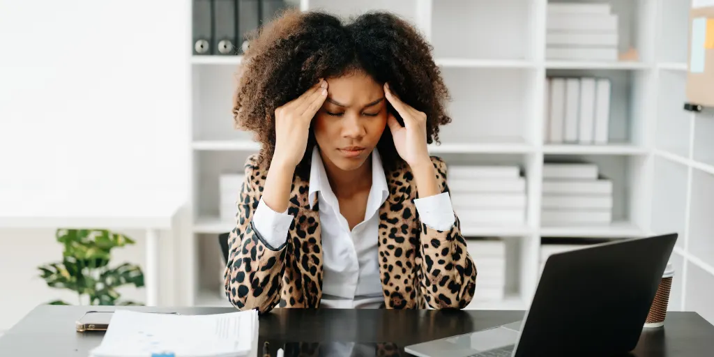 African Woman who is tired and overthinking from working with tablet and phone from modern office
